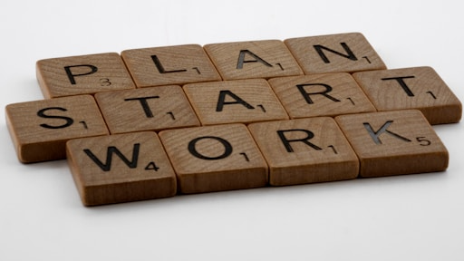 A photo of wooden tiles with letters on them spelling out 'Plan, Start, Work'