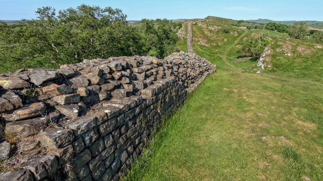 A photo of a stone wall in a grassy landscape