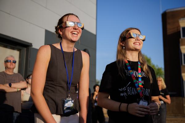 A photo of attendees of the stargazing event at RAL looking at the solar eclipse through eclipse glasses
